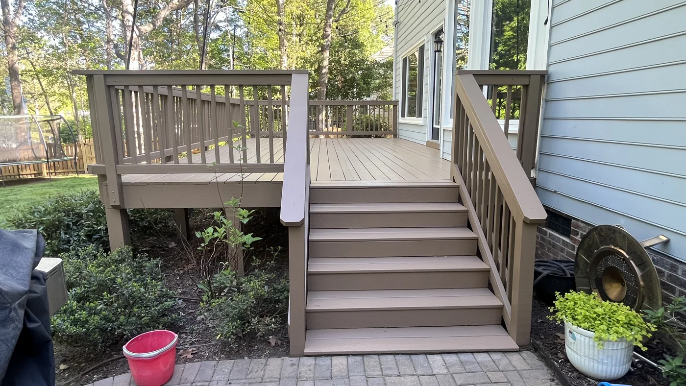 Finished deck stairs and railing beside a home